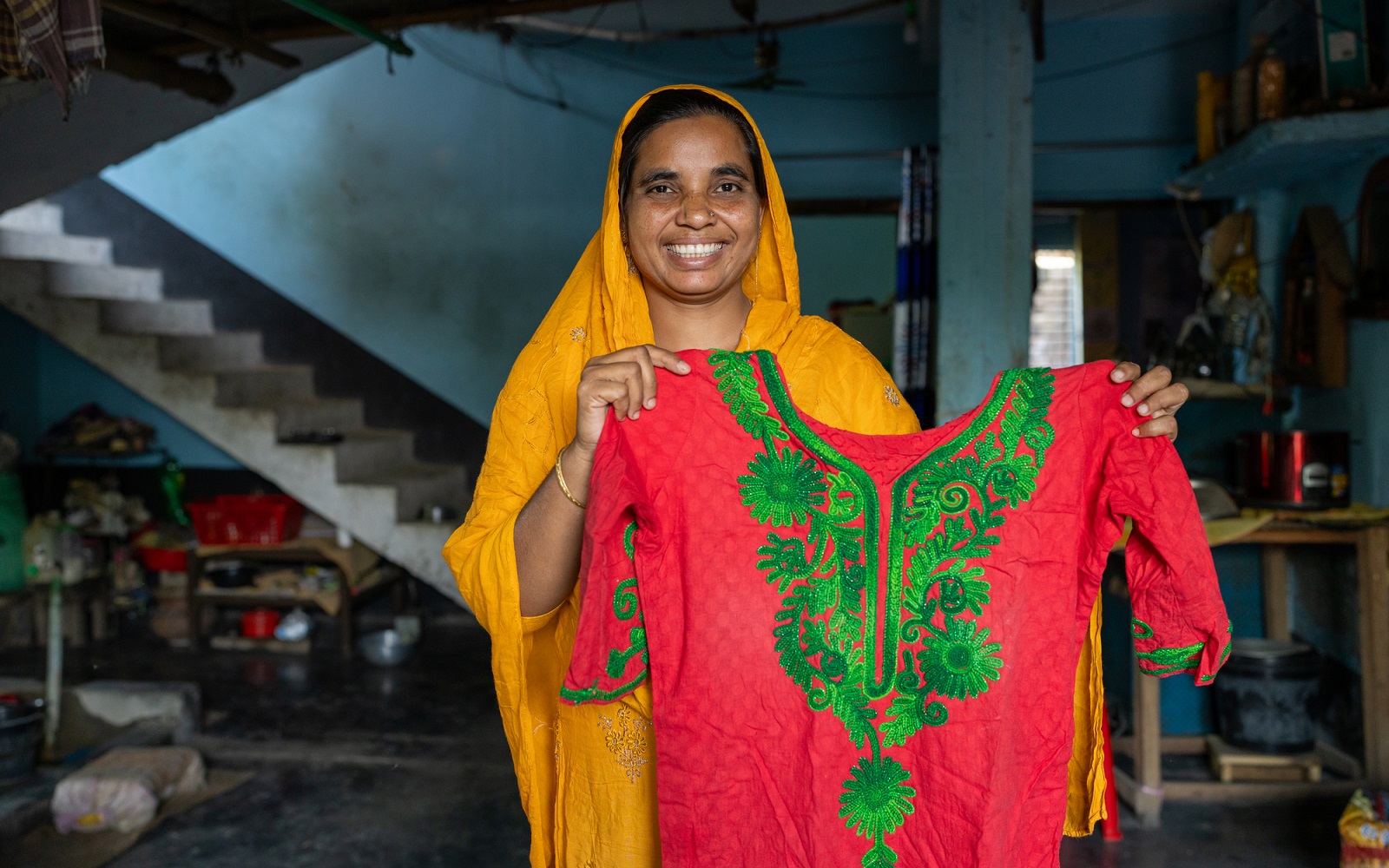 Morzina Begum (40), a tailor, shows off an item of clothing she recently made. Morzina embodies financial empowerment by being part of the SATHI Network in Rajshahi, Bangladesh, on April 2, 2024.The SATHI Network is a dedicated women-led agent network spanning across the country, to ensure convenient access to financial services for marginalized women at the last mile. Women agents in rural areas foster a sense of trust and comfort among female customers, enabling them to engage more confidently in financial transactions. The gender-specific intervention promotes financial inclusion and empowering un/underbanked women in a safe and supportive environment.