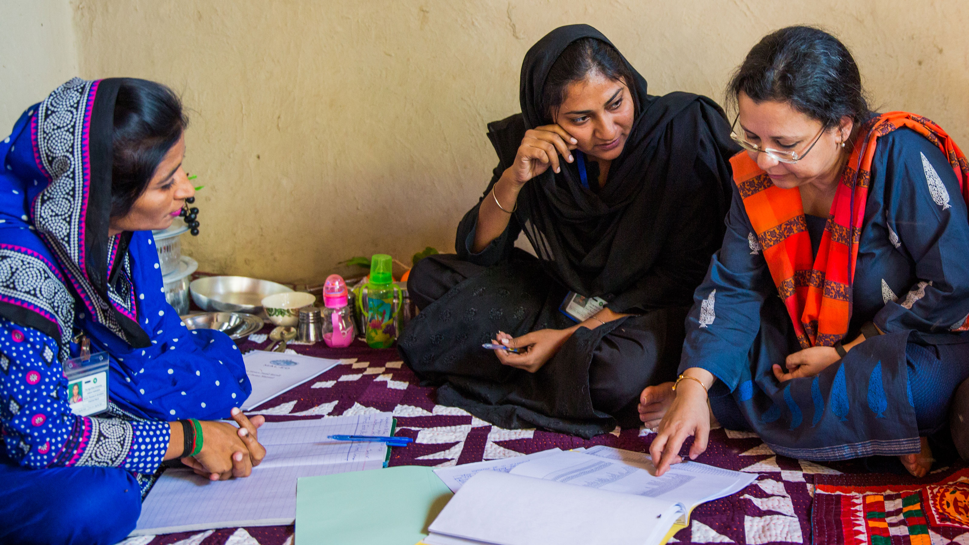 Dr. Anita Zaidi with local women reviewing documents on a patterned rug