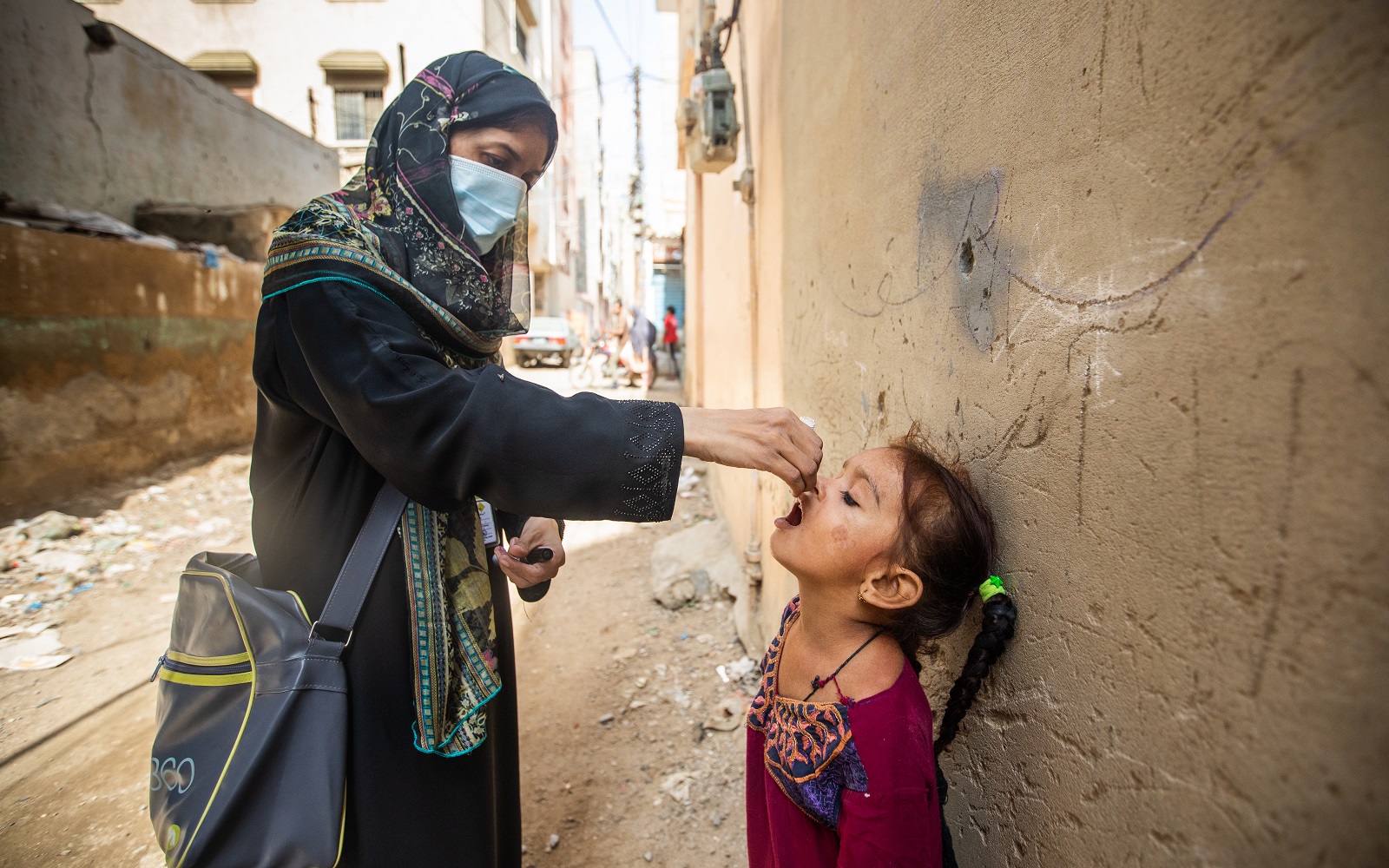 A health worker provides oral polio vaccine to a young girl