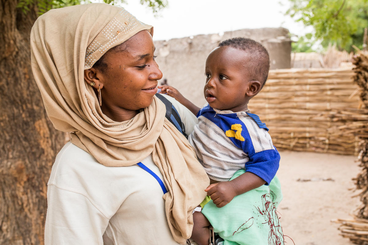 A caregiver holding a young child